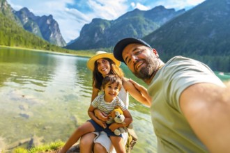 Tourists enjoying summer holidays by a picturesque alpine lake, capturing joyful moments with their
