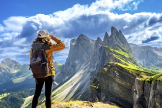 Hiker shielding her eyes while enjoying the breathtaking view of the odle mountain range in the