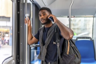 Busy african casual businessman talking to the mobile on the bus on the way to work