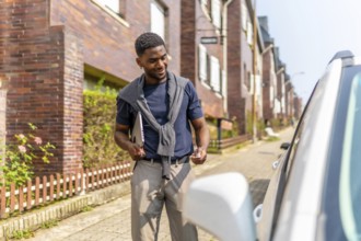 African man opening the car with a remote control on the street on the way to work carrying a