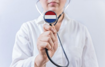 Female doctor holding stethoscope with Dutch flag. National health system of Netherlands