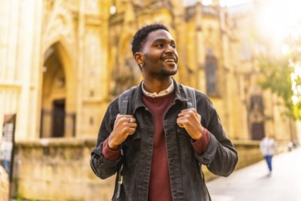 African man with casual clothes and rucksack enjoying visiting a city during sunset