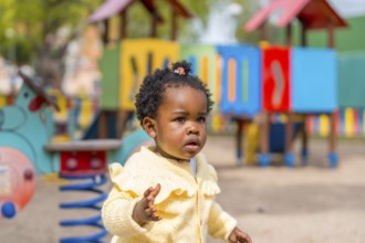 A little african girl playing on playground under the sun
