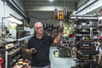 Mature caucasian man using remote control to operating a crane in a metal factory
