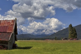 A peaceful alpine landscape with meadows, an old barn and mountains in the background, Wallgau,