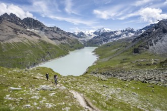 Two mountaineers on a hiking trail, view of a blue mountain lake, Lac des Dix reservoir, mountain