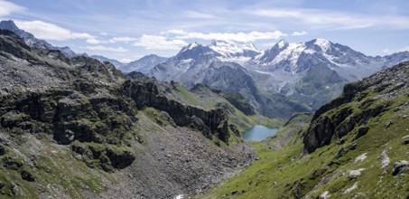 Mountain stream and mountain lake Lac de Louvie with glaciated summit of the Grand Combin, Val de