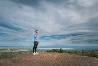 Young man talking on the phone at a viewpoint surrounded by nature. Man talking on the phone at a