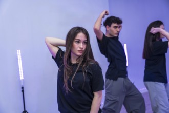 Group of young dancers practicing a modern choreography in a dance studio illuminated by purple