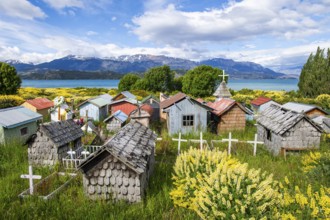 Colourful plastic flowers and graves with miniature houses made of corrugated iron and wooden