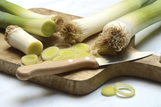 Leek, leek sticks and leek rings on a chopping board with a knife