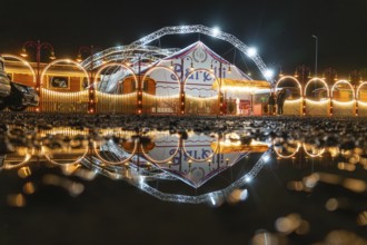 Nocturnal circus reflected in a pool of water, with illuminated arches and lights, Böblingen,