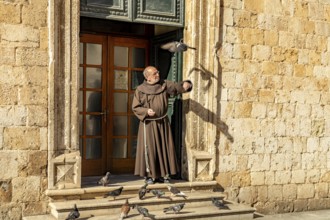Monk feeding the pigeons in front of the Franciscan monastery in Dubrovnik, Croatia, Europe