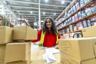 Adult caucasian happy woman working in a distribution warehouse organizing boxes to deliver
