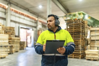 Man doing inventory writing notes on clipboard in the carpentry area of a recycling plant
