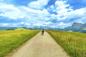 Mother and son walking on gravel path at alpe di siusi enjoying summer landscape in the dolomites,