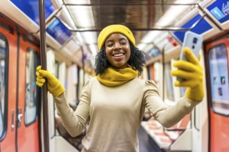 Smiling young woman wearing yellow winter accessories takes a selfie with smartphone while