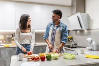 Young smiling couple preparing a healthy salad together in their modern kitchen, enjoying their