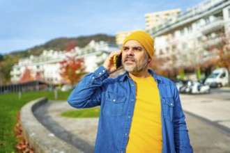 Modern mature man talking to the mobile walking down the street