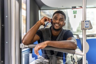 Young african confident businessman with casual clothes talking to the mobile while traveling by