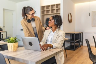 Two female colleagues collaborating on a project, demonstrating teamwork and support in a modern