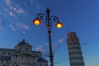 The Cathedral of Santa Maria Assunta and the Leaning Tower under an illuminated street lamp in the
