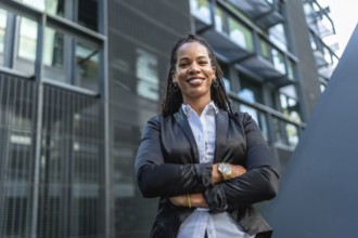 Migrant latin confident woman standing with arms crossed smiling at camera in a financial district