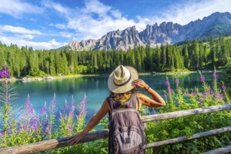 Female tourist admiring the stunning turquoise waters of lake carezza with latemar mountain range