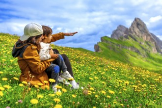 Mother and child admiring the landscape in the seceda mountains in the dolomites, italy, during a
