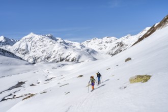 Two ski tourers in a mountain landscape with snow, behind Piz Müsella, ascent to Grialetsch
