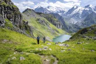 Hiker and mountain lake Lac de Louvie with glaciated summit of the Grand Combin, Val de Bagnes,