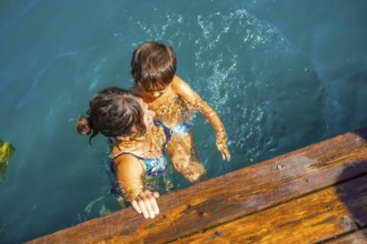 Mother and son having fun swimming in the turquoise water of lake bled, a popular tourist