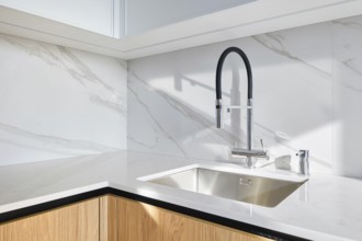 A contemporary kitchen showcases a stylish sink integrated into smooth marble countertop. The