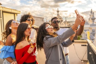 Stylish friends taking selfie in a rooftop while celebrating party with wine