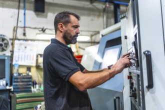 Side view of a mature caucasian man working in the control station of a cnc factory