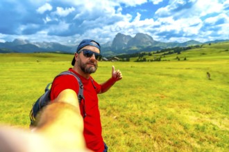 Backpacker taking selfie showing thumbs up sign enjoying beautiful summer landscape at alpe di