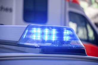 Close-up of flashing blue lights during a police operation with an ambulance in the background