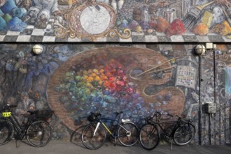 Bicycles in front of a house wall with large-format graffiti of a colour palette, Sølvgades Skole,