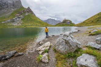 Mountaineer in yellow jacket at the mountain lake, view over the Wolayersee lake to the alpine club