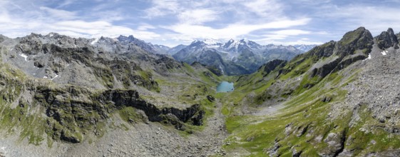 Alpine panorama, aerial view, mountain stream and mountain lake Lac de Louvie with glaciated summit
