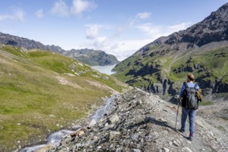 Mountaineers on a hiking trail by a mountain stream, behind the Lac des Dix reservoir, Valais Alps,