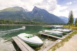 Jetty with boats at Hintersee, with green mountains in the background, peaceful and idyllic natural