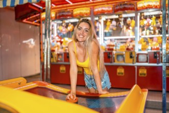 Blonde woman smiling at camera playing hockey at a fair at night