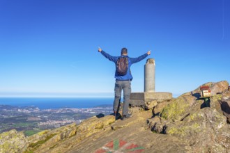 A man with his arms raised on the summit of Mount Adarra in Urnieta. Gipuzkoa, Basque Country
