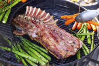 Barbecue with Easter roast. Rack of lamb and green asparagus grilled on an outdoor kettle barbecue.
