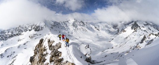 Three mountaineers climbing the narrow ridge of Piz Laviner, view of mountain panorama in winter