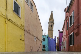 City view of Burano with colourfully painted houses and canals. Slate church tower Campanile,