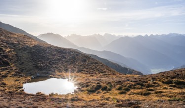 Small mountain lake on the Krahberg, sun star in the morning, mountain panorama in autumn, Venet