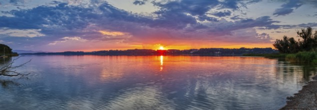 Dramatic sunset over a calm lake with reflecting water, Simssee