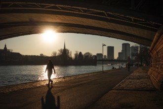 Passers-by walking along the banks of the Main at sunset in Frankfurt, Frankfurt am Main, Hesse,